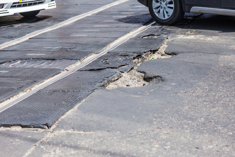 Very bad quality road with potholes. Hole in asphalt, bad asphalt. Pit, unsafe, hole road. Transportation, destruction of roads, risk of movement by car concept. Bad roads concept Repair & Maintenance